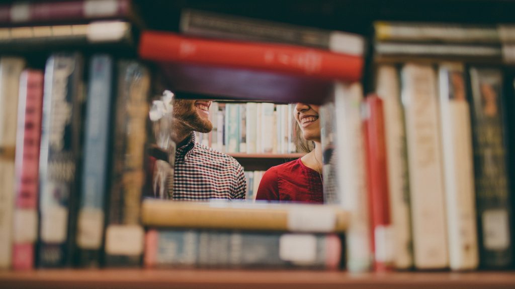 dwie osoby w bibliotece, uśmiechające się do siebie